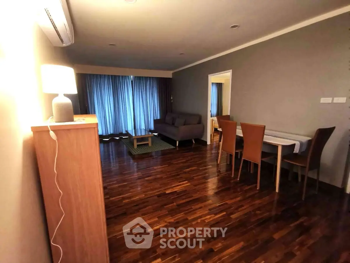 Spacious living room with wooden flooring and modern furniture in a cozy apartment.