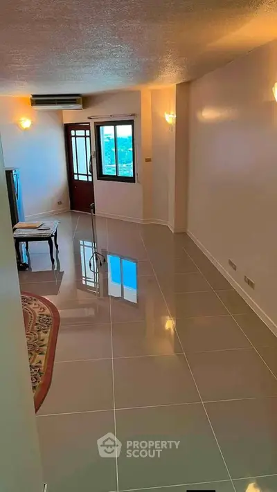 Spacious living room with glossy tiled floors and natural light, ideal for modern living.