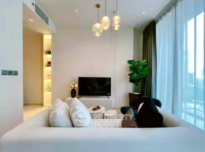 Modern living room with cozy sofa, stylish lighting, and large windows offering city views.