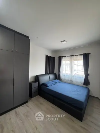 Modern bedroom with sleek furniture and large window for natural light.