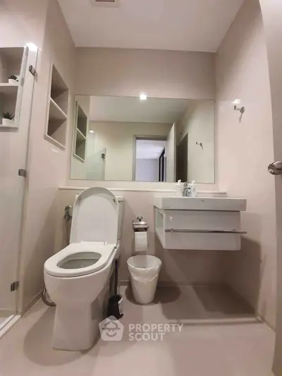 Modern bathroom with sleek fixtures and large mirror, featuring a shower and toilet in a minimalist design.