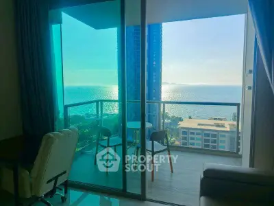 Stunning ocean view from modern apartment balcony with cozy seating area.
