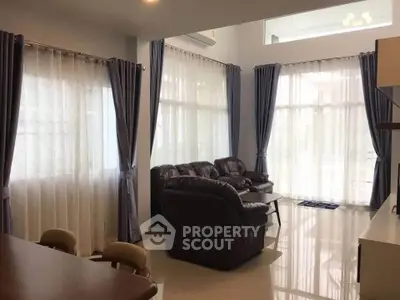 Spacious living room with elegant curtains and leather sofas, perfect for family gatherings.