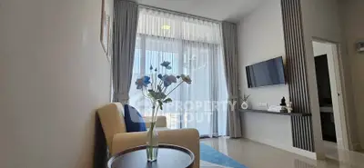Modern living room with elegant decor and large window, featuring a cozy armchair and wall-mounted TV.