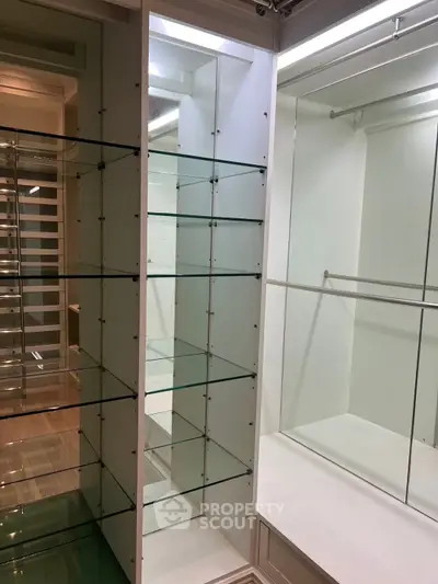Spacious walk-in closet with glass shelving and ample storage space.
