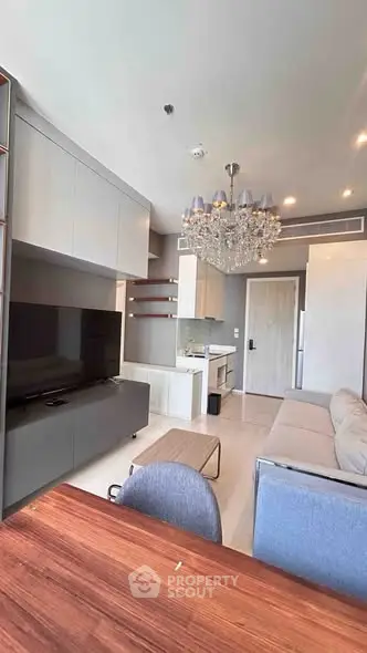 Modern living room with elegant chandelier and sleek furniture in a stylish apartment.