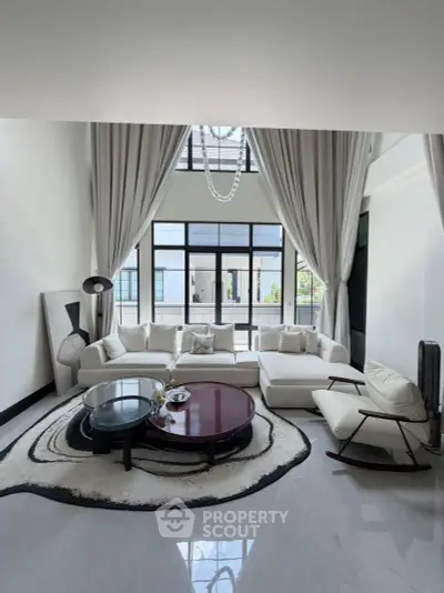Luxurious living room with high ceilings, elegant decor, and large windows offering natural light.