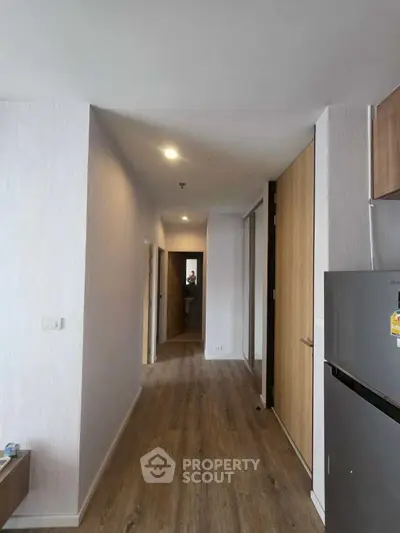 Modern apartment hallway with wooden flooring and sleek refrigerator