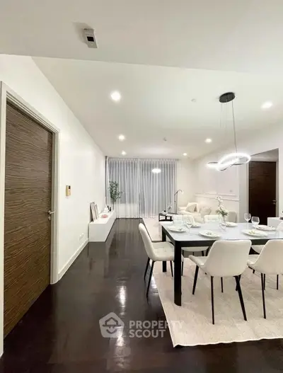 Elegant dining area with modern lighting and sleek dark flooring in a spacious apartment.