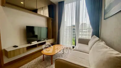 Chic modern living room with large TV, cozy sofa, and floor-to-ceiling windows offering city views.