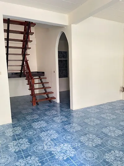 Spacious interior with unique blue patterned flooring and elegant wooden staircase