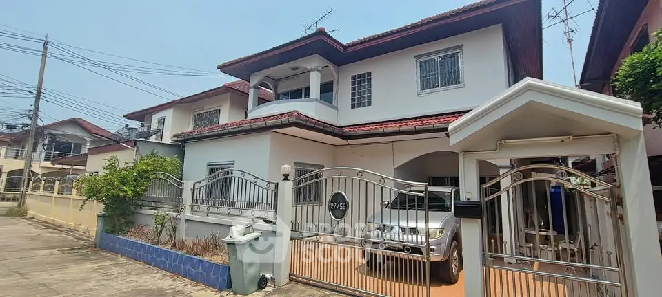 Charming two-story house with gated entrance and carport in a suburban neighborhood.