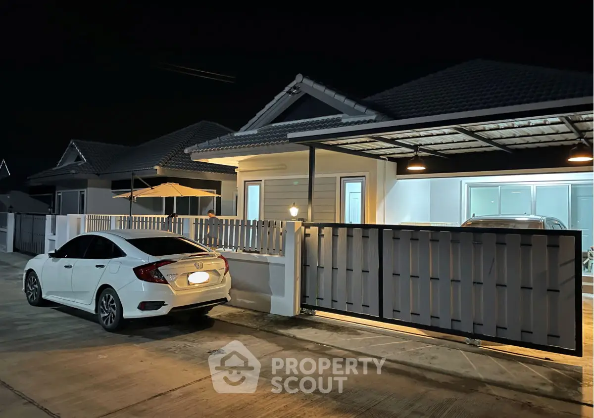 Modern suburban house with carport and parked car at night, showcasing sleek exterior design.