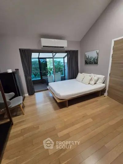 Modern bedroom with wooden flooring and balcony access in stylish apartment