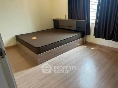 Spacious bedroom with modern bed frame and large windows for natural light.