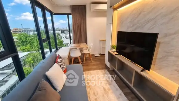 Modern living room with large windows and city view, featuring stylish furniture and cozy ambiance.