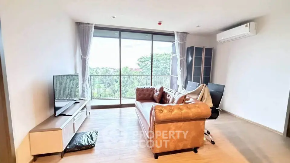 Spacious living room with leather sofa and large windows offering a scenic view.