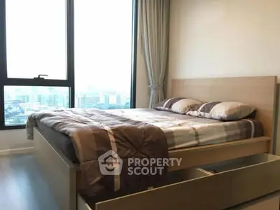 Modern bedroom with large window offering city view, featuring a stylish bed and neutral decor.