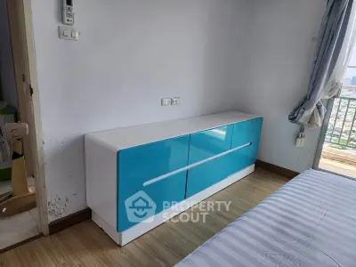 Modern bedroom with sleek blue dresser and balcony view, perfect for urban living.