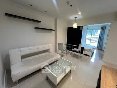 Modern living room with sleek white furniture and open view to bedroom