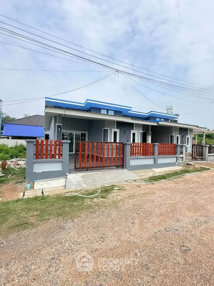Charming single-story house with blue roof and wooden fence in a serene neighborhood.