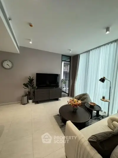 Modern living room with sleek furniture and large windows for natural light.