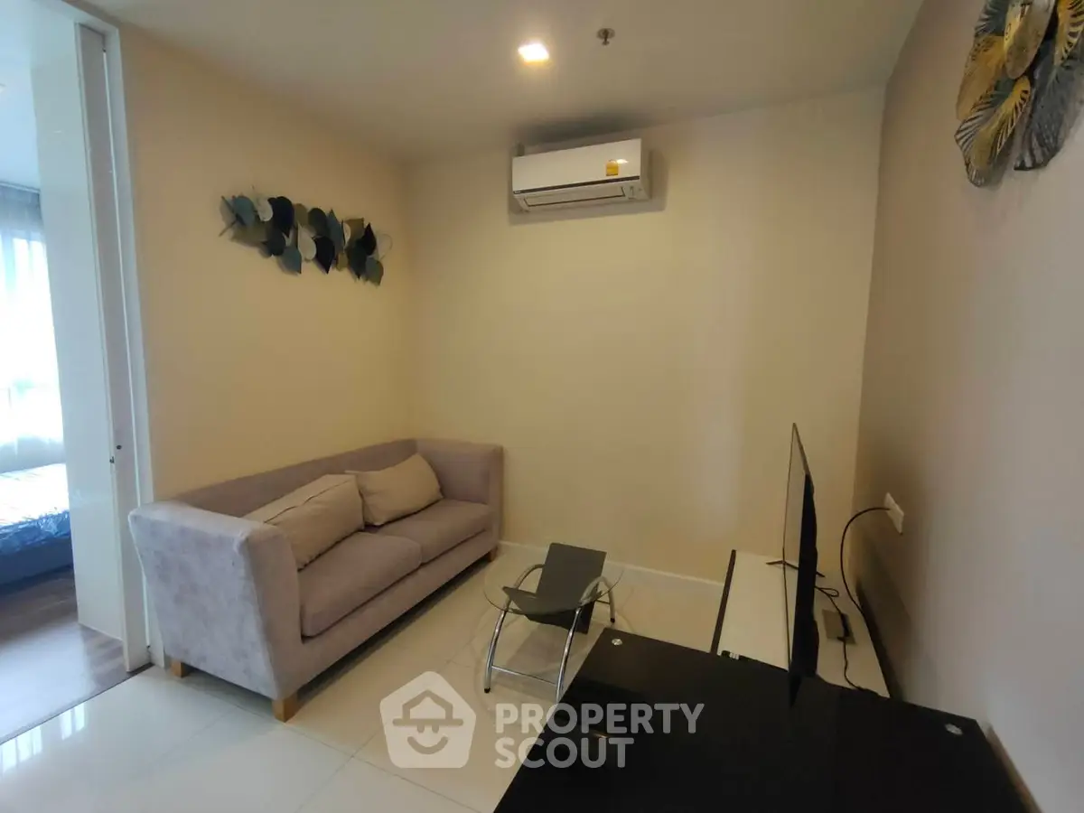 Modern living room with sleek design and air conditioning, featuring a cozy sofa and flat-screen TV.