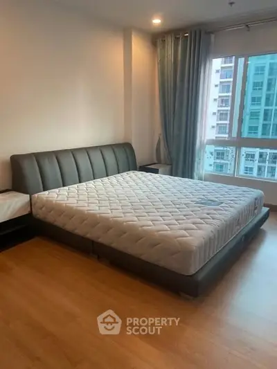 Spacious bedroom with modern bed and large window offering city view