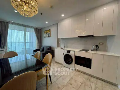 Modern open-plan kitchen and living area with elegant chandelier and balcony view.