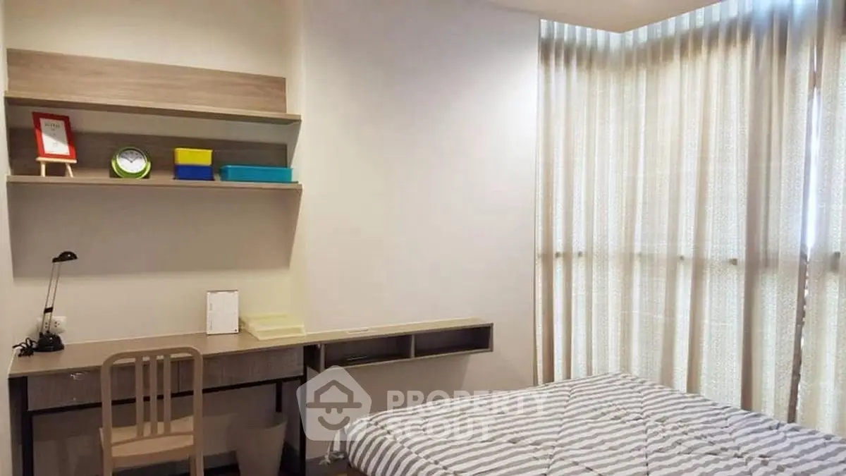 Cozy bedroom with study area and natural light, perfect for relaxation and productivity.