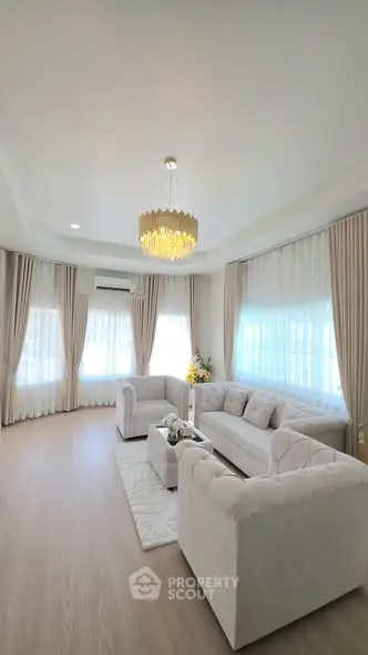 Elegant living room with plush sofas, chandelier, and large windows for natural light.