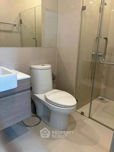 Modern bathroom with glass shower and sleek fixtures in contemporary apartment.