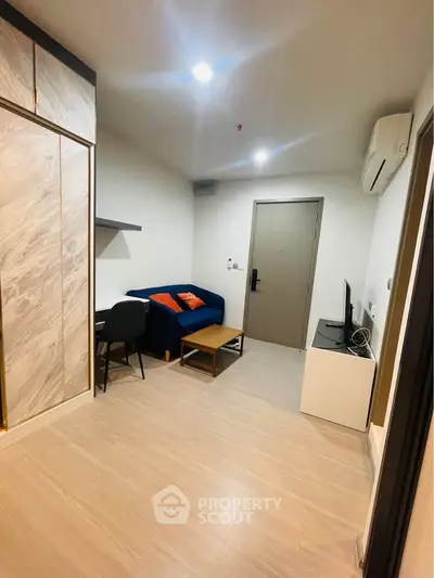 Modern living room with sleek design, featuring a cozy sofa, TV, and stylish decor in a compact space.