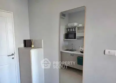 Modern compact kitchen with microwave and sink in a minimalist apartment.