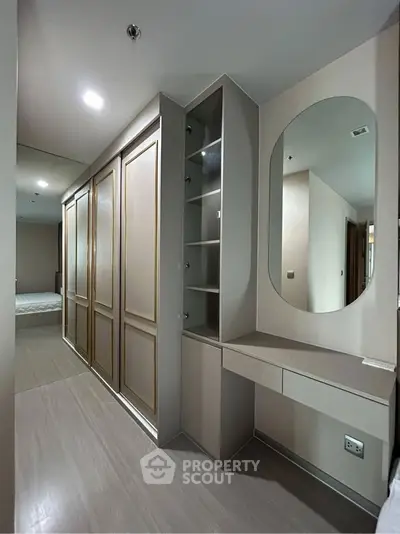 Elegant bedroom with built-in wardrobe and vanity mirror in modern apartment