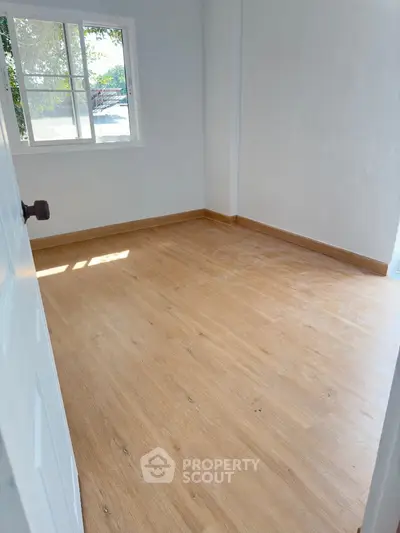 Bright and airy empty room with natural light streaming through a large window, showcasing the potential for personalization in a serene setting.