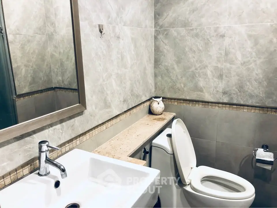 Modern bathroom with elegant fixtures and neutral tones, featuring a sleek sink and toilet.