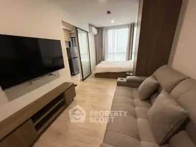 Modern studio apartment with cozy living area and bedroom, featuring sleek furniture and natural light.