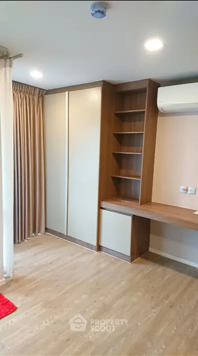 Modern study room with built-in desk and shelving, featuring wood flooring and air conditioning.