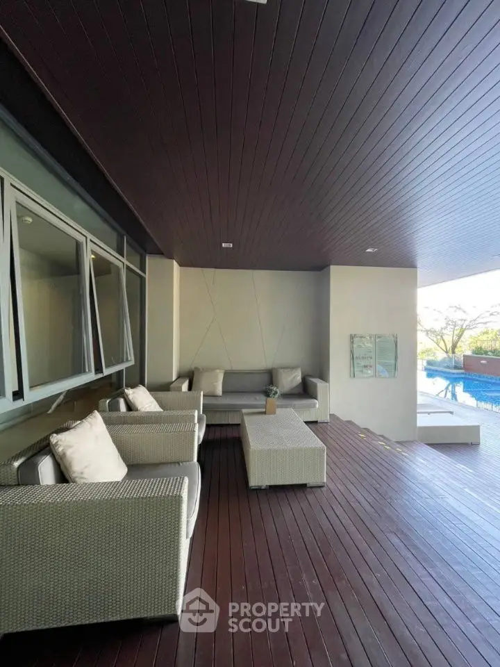 Luxurious poolside patio with modern seating and wooden deck, perfect for relaxation and entertaining.