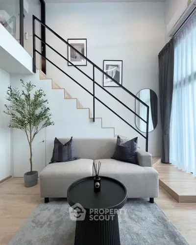 Modern living room with stylish staircase and cozy seating area in a bright, airy space.