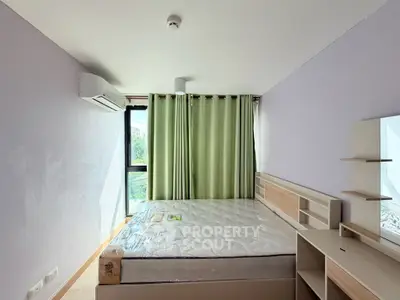 Spacious bedroom with large window and modern furnishings, perfect for comfortable living.