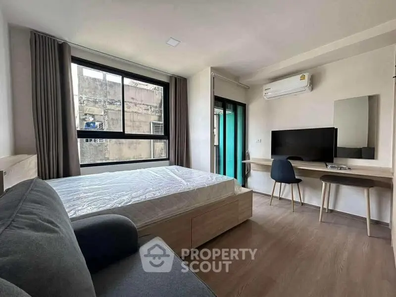 Modern bedroom with large window, air conditioning, and stylish furniture in urban apartment.