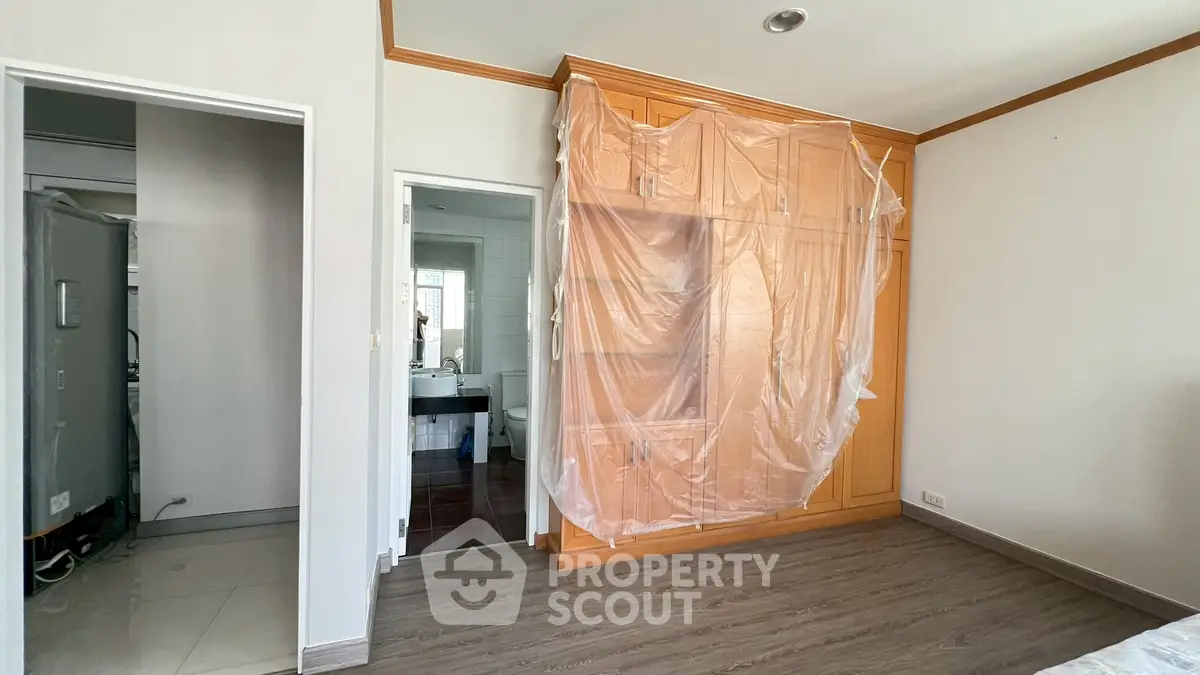 Spacious bedroom with wooden wardrobe and en-suite bathroom, ideal for modern living.