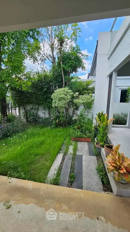 Charming garden view from a modern home with lush greenery and sleek architecture.