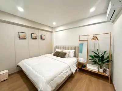 Modern bedroom with cozy decor, wooden flooring, and stylish lighting, perfect for relaxation and comfort.