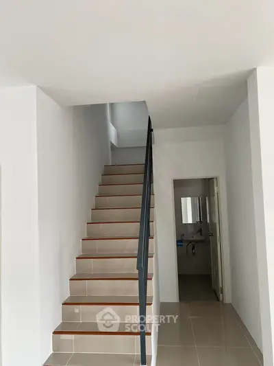Modern staircase with sleek design leading to upper floor in a minimalist home interior.