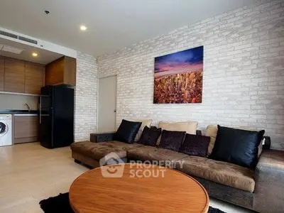 Modern living room with stylish decor and compact kitchen area, featuring a cozy sofa and vibrant wall art.