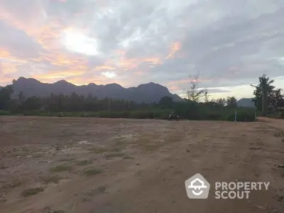 Scenic land plot with mountain views at sunset, ideal for development or investment opportunities.