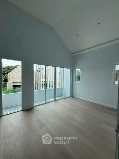 Spacious modern living room with high ceilings and large windows offering natural light and serene views.